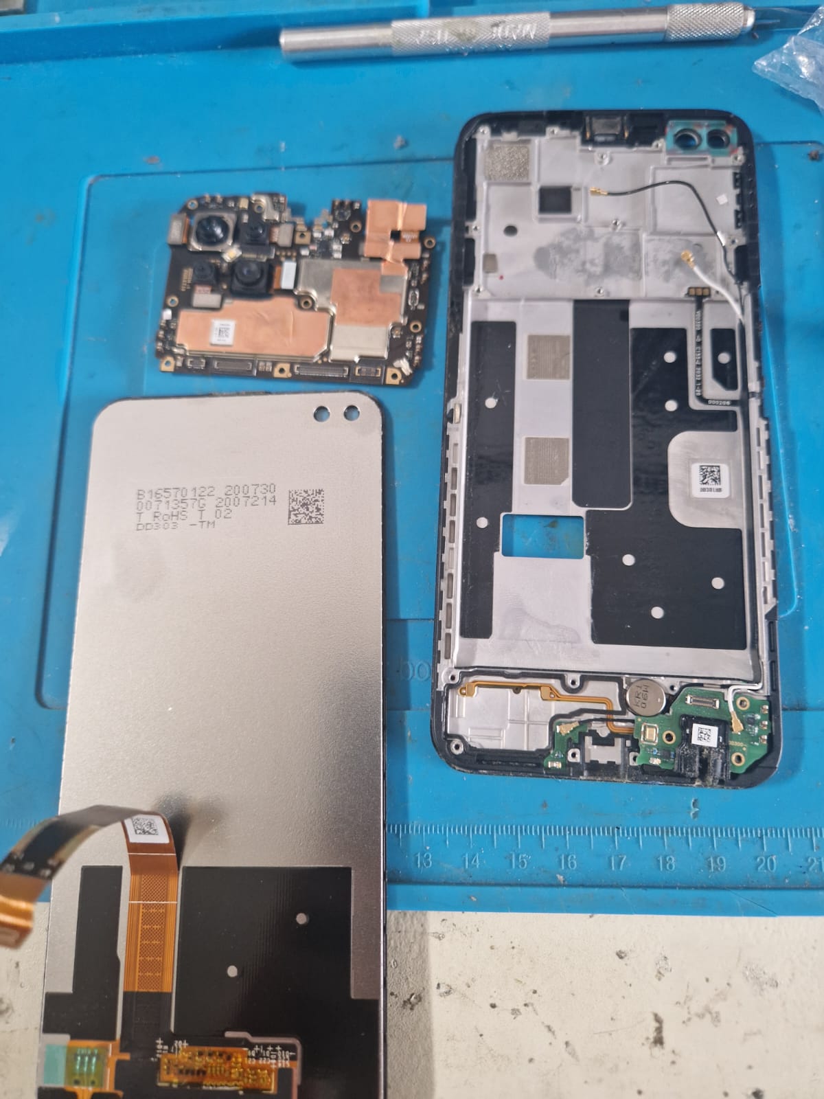Carte mère Oppo et module caméra posés sur le tapis d'atelier